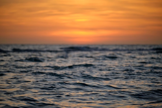 Drammatiche onde rosse dell'oceano al tramonto con morbide acque scure del mare serale