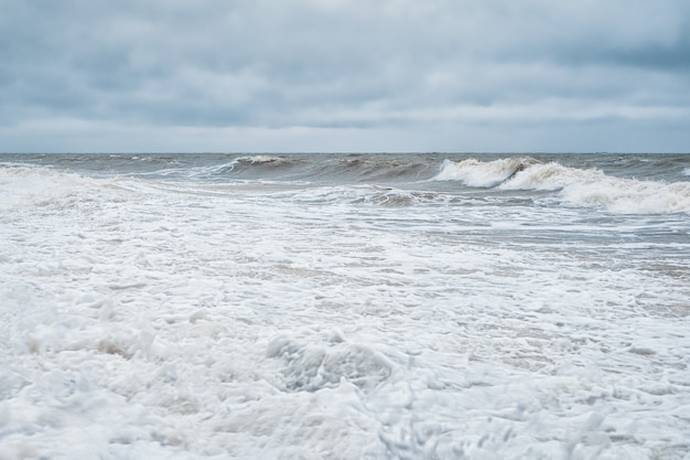 Drammatico paesaggio marino minimalista con onde e schiuma bianca sul mare bianco.