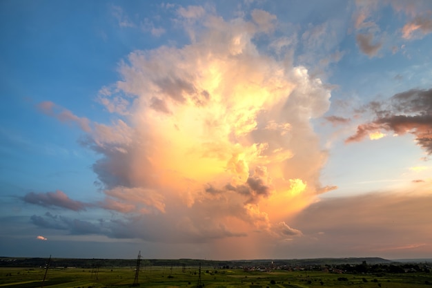 Drammatico tramonto giallo sopra la zona rurale con tempestose nuvole gonfie