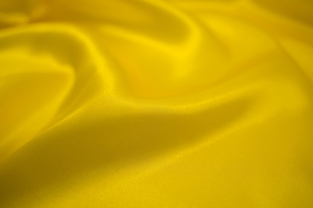 Drappo tessile in tessuto di stoffa setosa in raso dorato astratto con sfondo piega ondulato