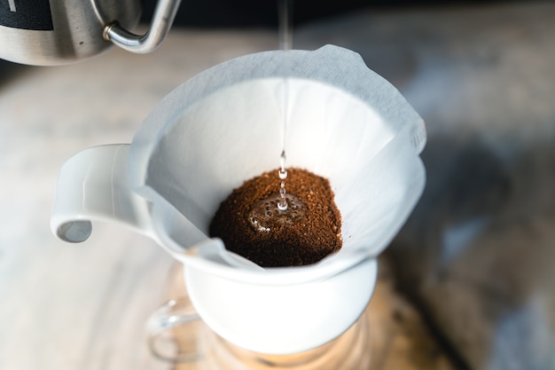 Drip coffee, barista versando acqua sul caffè macinato con filtro, erogazione del caffè