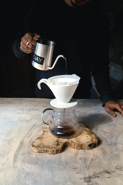 Drip coffee, barista versando acqua sul caffè macinato con filtro, erogazione del caffè