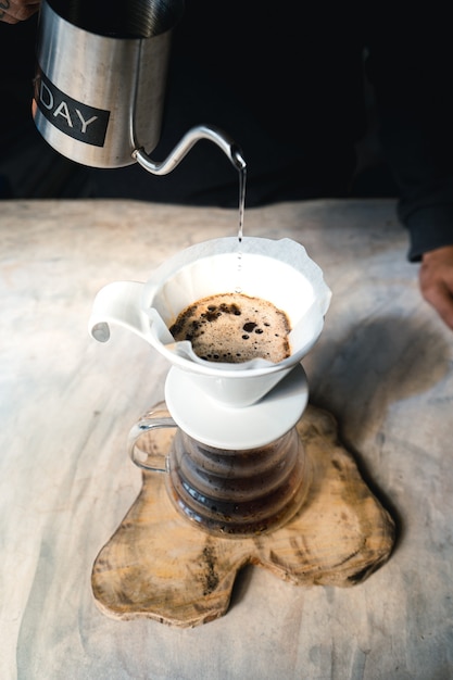 Drip coffee, barista versando acqua sul caffè macinato con filtro, erogazione del caffè