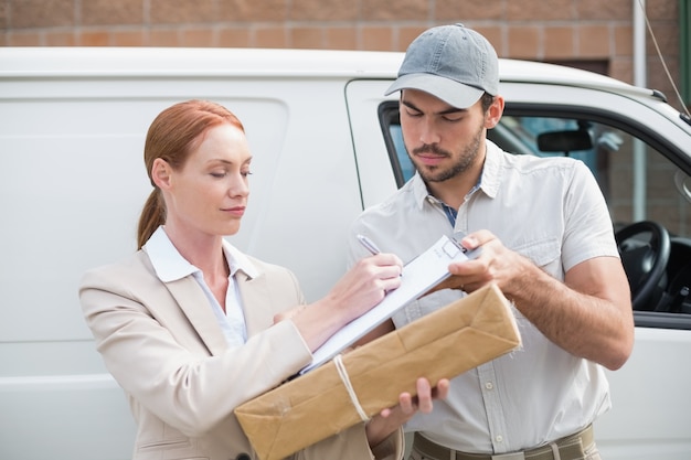 Driver di consegna che passa pacco al cliente fuori van