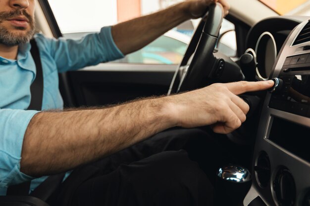 Driver maschio che spinge il pulsante di controllo sul pannello che guida l'auto ritagliata
