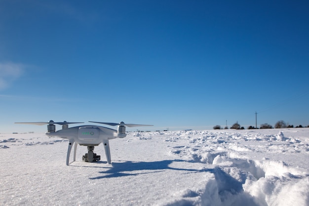 Drone che vola sopra il campo coperto di neve nella soleggiata giornata invernale