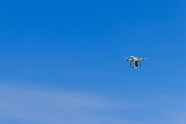 Drone con telecamera che vola nel cielo blu