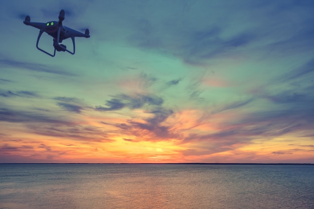 Drone quadrocopter con telecomando silhouette scura contro il tramonto colorato soft focus tonico