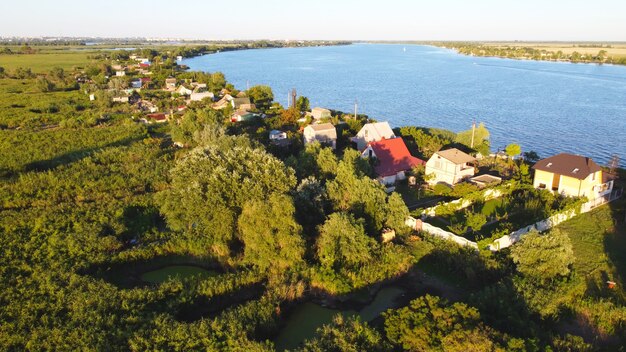 Drone sorvola un fiume ondeggiante di colore blu circondato da un villaggio locale con vari edifici