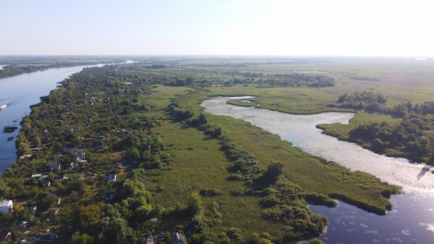 Drone sorvola un fiume ondeggiante di colore blu circondato da un villaggio locale con vari edifici