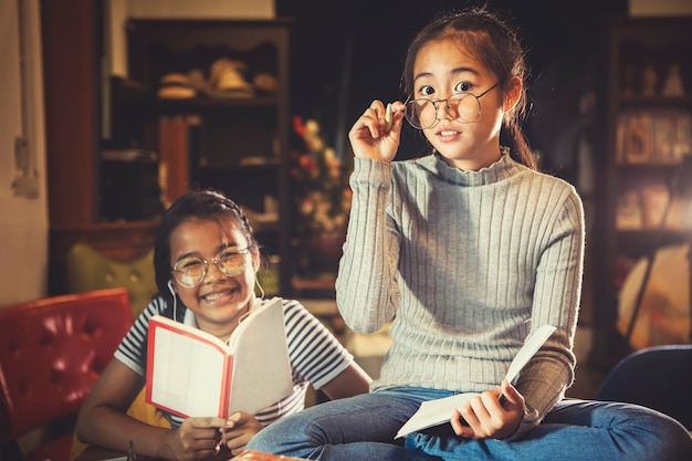 Due adolescente asiatico e booket a disposizione che si siedono nella biblioteca