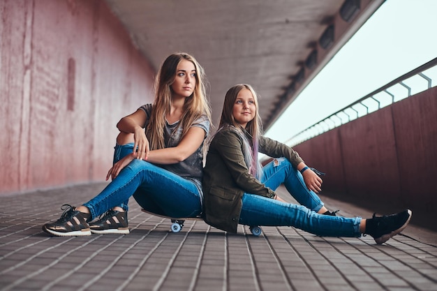 Due adolescenti attraenti e amichevoli sono seduti sullo skateboard in un lungo tunnel.