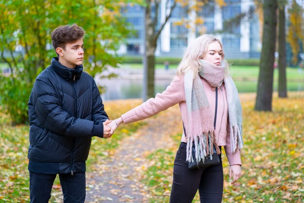 Due adolescenti innamorati in lite. La ragazza bionda si offende al ragazzo, il ragazzo le tiene la mano,