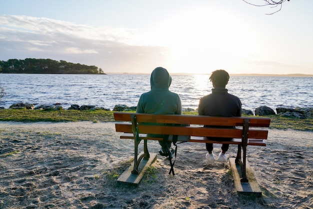 Due adolescenti seduti su una panchina sulla spiaggia del lago lacanau in Francia a guardare un tramonto