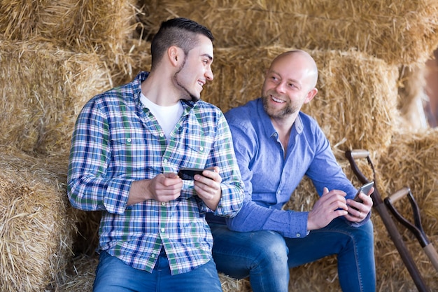 Due agricoltori con i telefoni al fienile