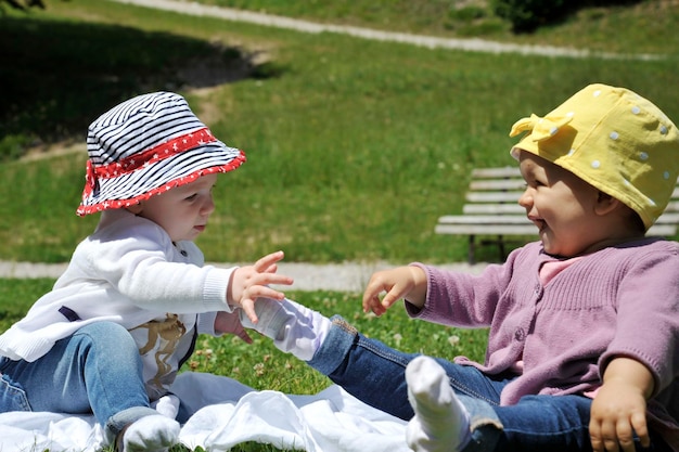Due allegre bambine caucasiche che giocano insieme sull'erba nel parco Concetto di maternità infanzia amicizia e vacanze estive