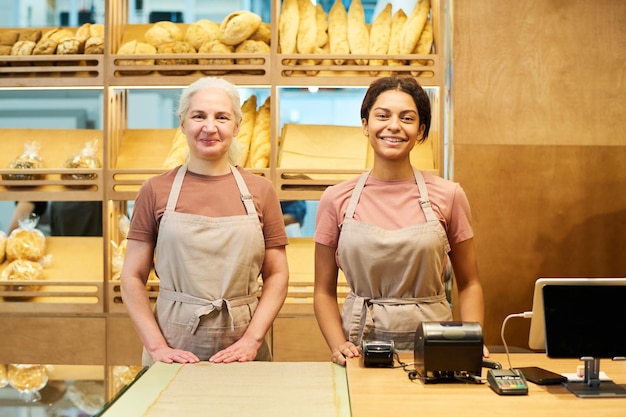 Due allegre impiegate in uniforme in piedi accanto alla scrivania