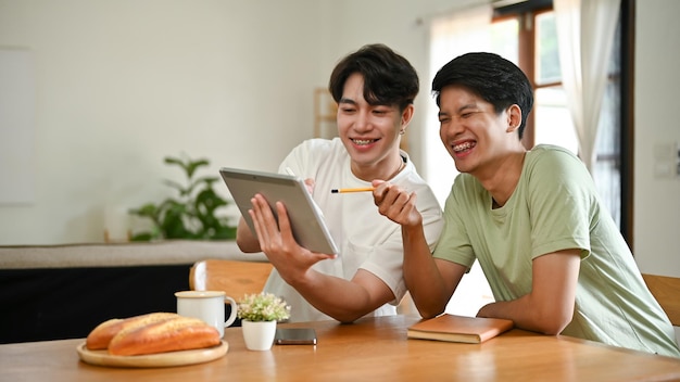 Due allegri uomini asiatici stanno guardando video divertenti su Internet attraverso un tablet