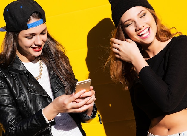 Due amiche adolescenti in abito hipster all'aperto fanno selfie su un telefono