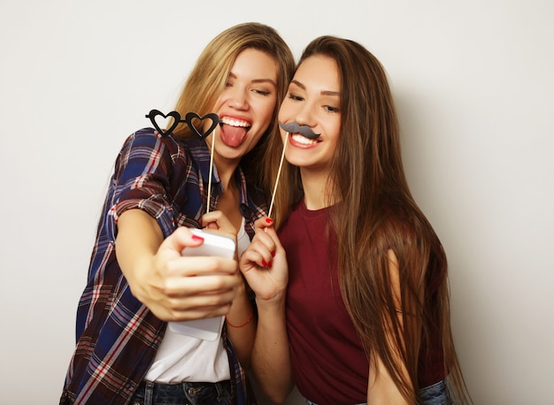 Due amiche adolescenti in abito hipster fanno selfie su un telefono.