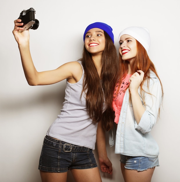 Due amiche adolescenti in abito hipster fanno selfie su un telefono.