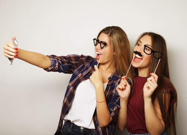 Due amiche adolescenti in abito hipster fanno selfie su un telefono.