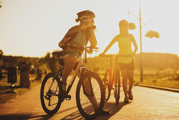 Due amiche che guidano sulle bici al tramonto