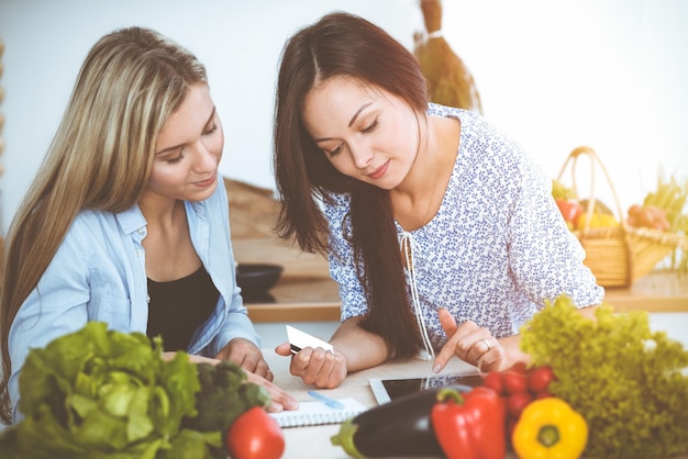 Due amiche che scelgono la ricetta per un pasto delizioso