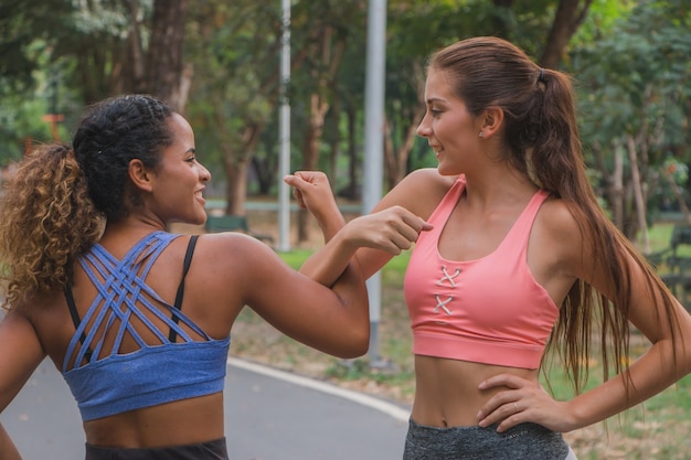 Due amiche che si estendono nel parco soleggiato