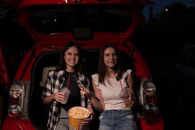 Due amiche con popcorn seduti in macchina mentre guardano un film al cinema Focus selettivo Concetto di hobby per attività ricreative di intrattenimento