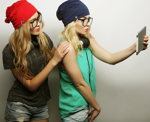 Due amiche hipster che si fanno selfie con tavoletta digitale