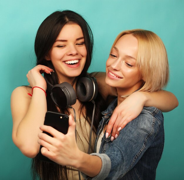 Due amiche in abito hipster fanno selfie su un telefono