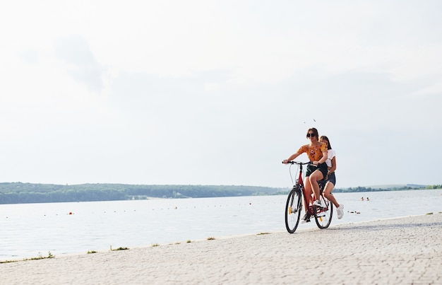 Due amiche in bici si divertono in spiaggia vicino al lago.