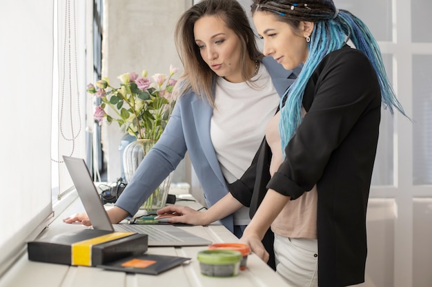 Due amiche partner della vendita di prodotti cosmetici in rete per la navigazione in Internet utilizzano il laptop