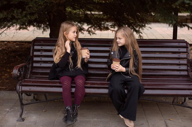 due amiche sono sedute su una panchina del parco con il cacao in mano, chiacchierando dolcemente