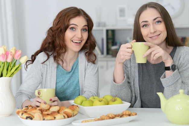 Due amiche sorridenti che si siedono al tavolo