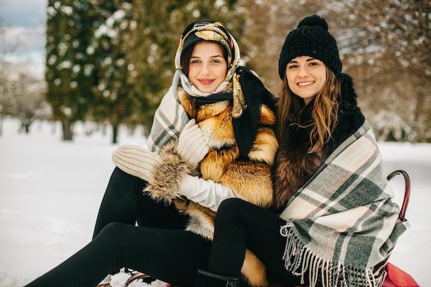 Due amiche sulle slitte in inverno