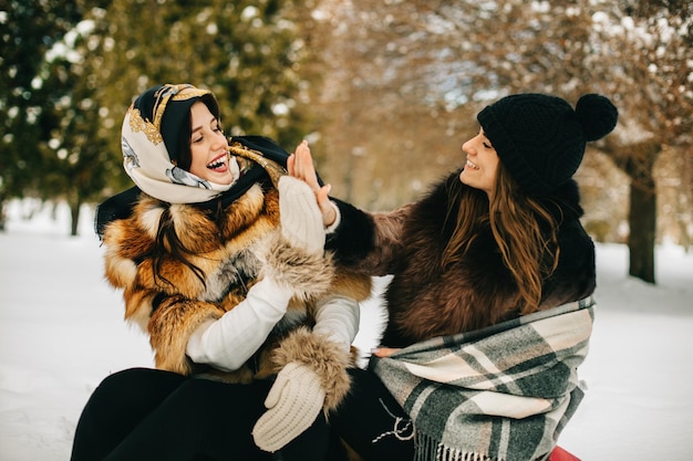 Due amiche sulle slitte in inverno