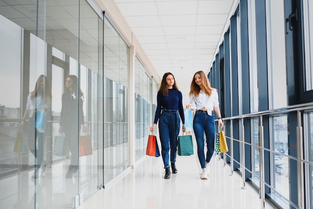 Due amiche sullo shopping camminano sul centro commerciale con i sacchetti