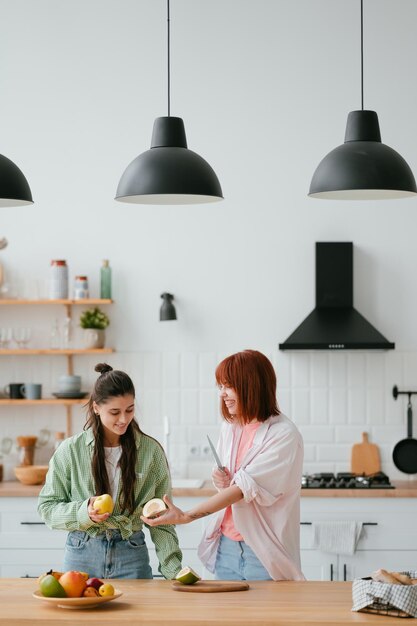 Due amiche tagliano la frutta in cucina