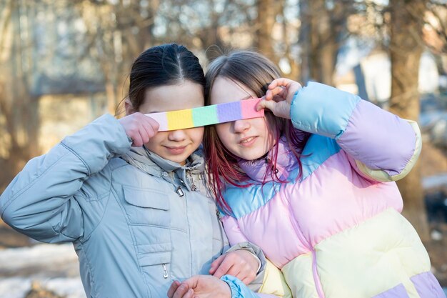 Due amici adolescenti si coprono gli occhi con del nastro adesivo color pastello