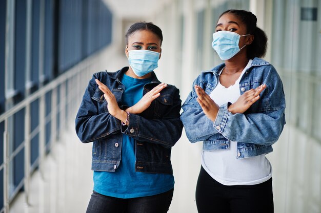 Due amici africani donna in giacca di jeans che indossa maschere protettive. Concetto di virus salute, medico.