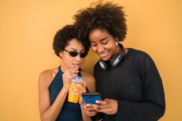 Due amici afro che usano il loro telefono cellulare.