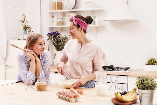 Due amici allegri cucinano insieme dolci e pettegolezzi in cucina