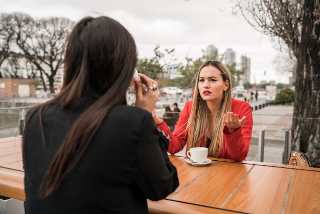 Due amici arrabbiati che discutono mentre sedendosi alla caffetteria.