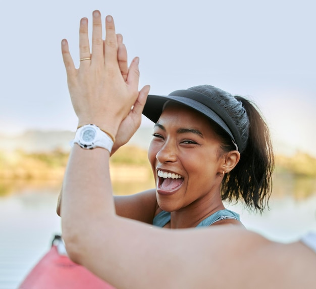 Due amici che condividono il cinque e celebrano il loro successo mentre sono attivi all'aperto Donna allegra in kayak e motivano il suo partner mentre si godono un'attività acquatica su un lago in estate