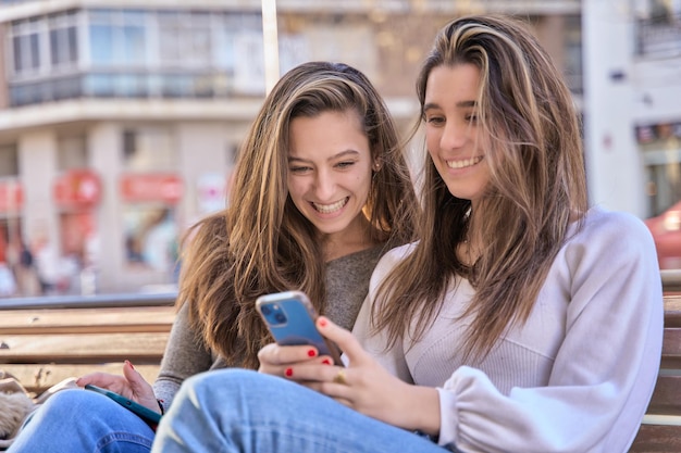 due amici che condividono lo smartphone guardando un video e ridendo