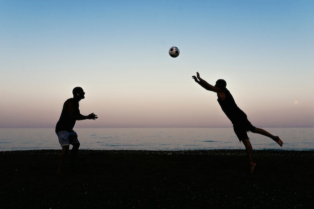 Due amici che giocano a calcio in spiaggia.