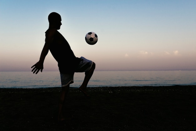 Due amici che giocano a calcio in spiaggia.