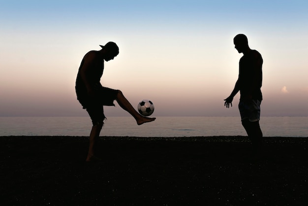 Due amici che giocano a calcio in spiaggia.